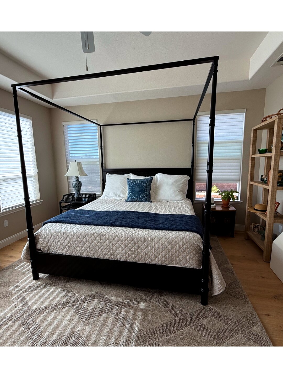Primary bedroom with a black four-poster bed, white quilted bedding, and navy accents