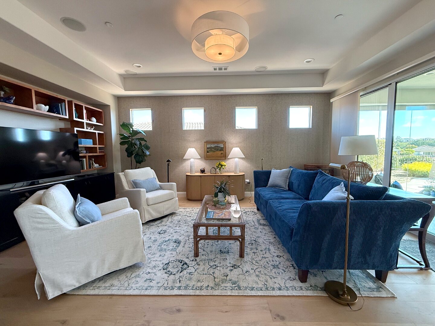 Living room after redesign — navy sofa, slipcovered chairs, and a curated gallery wall