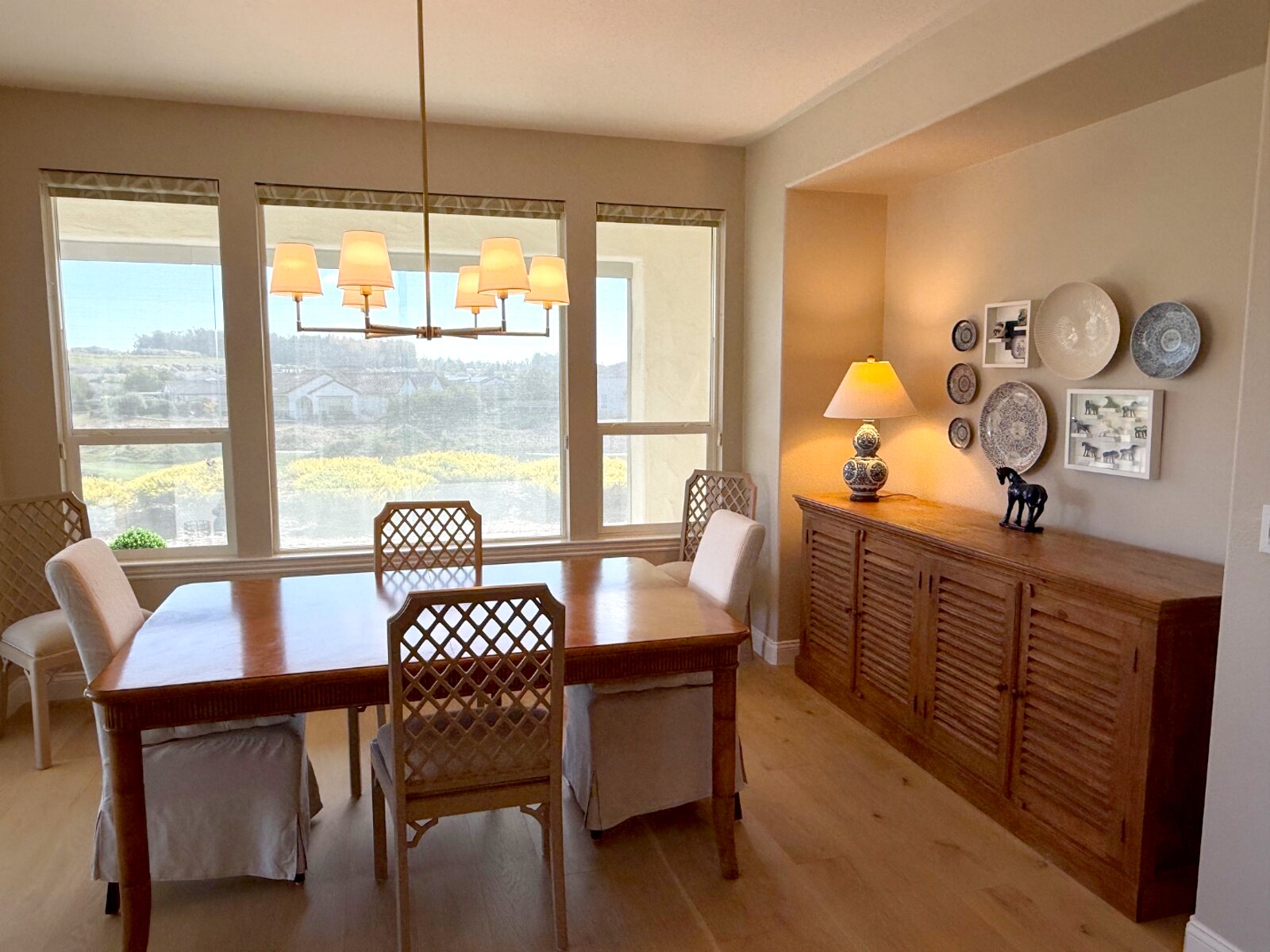 Dining room with wooden table, rope-wrapped chandelier, and gallery wall