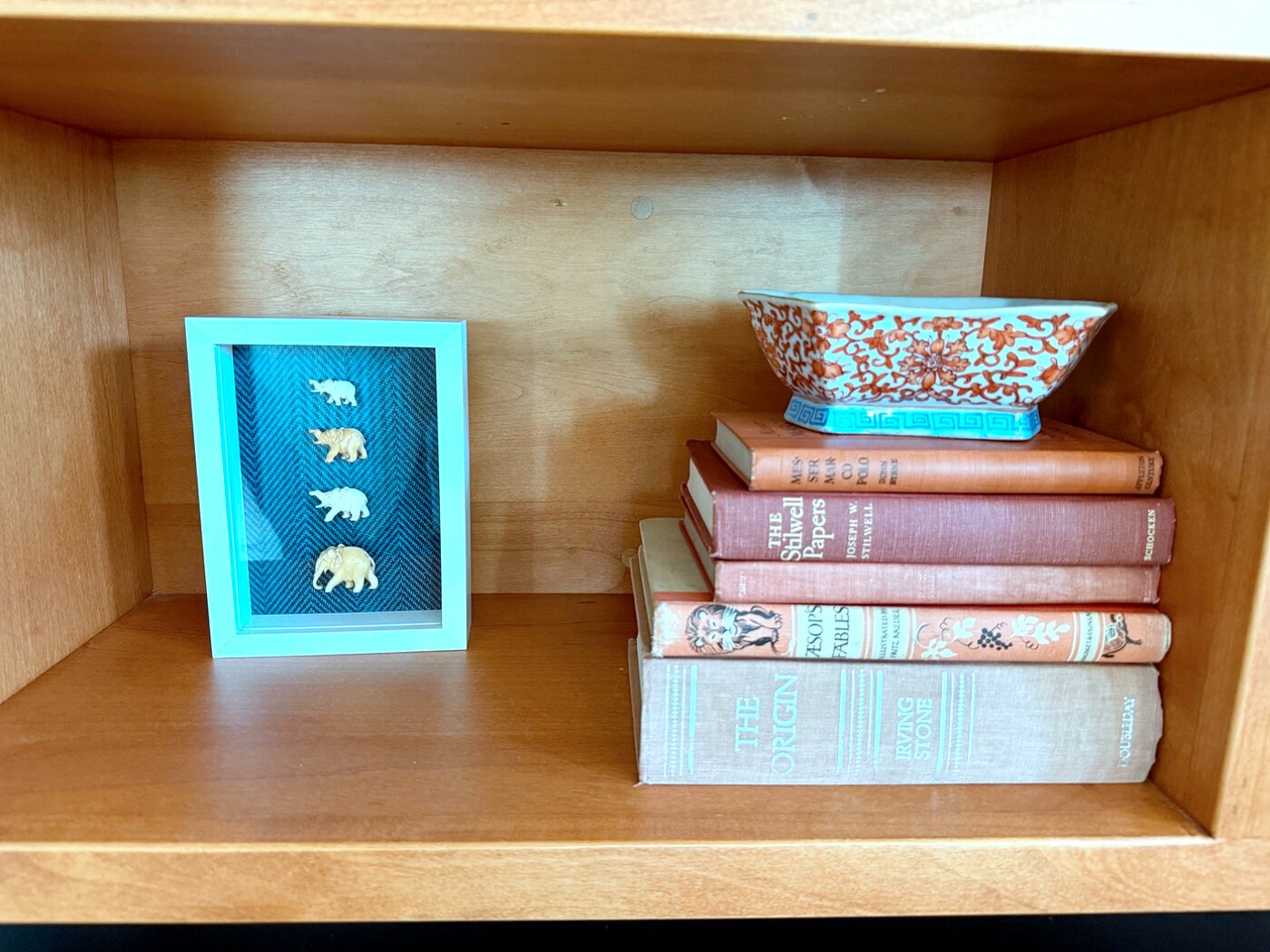 Bookshelf cubby styled with elephant figurines, vintage books, and a Chinoiserie bowl
