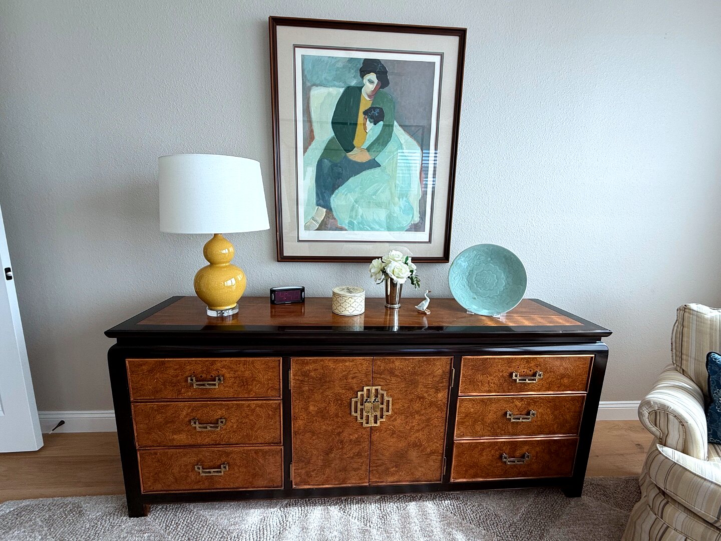 Hallway credenza with burl-wood fronts, gold hardware, and abstract portrait