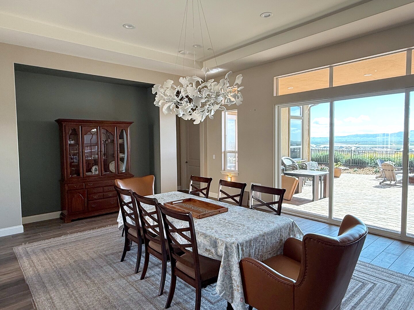Wide view of the dining room opening to a patio and green landscape