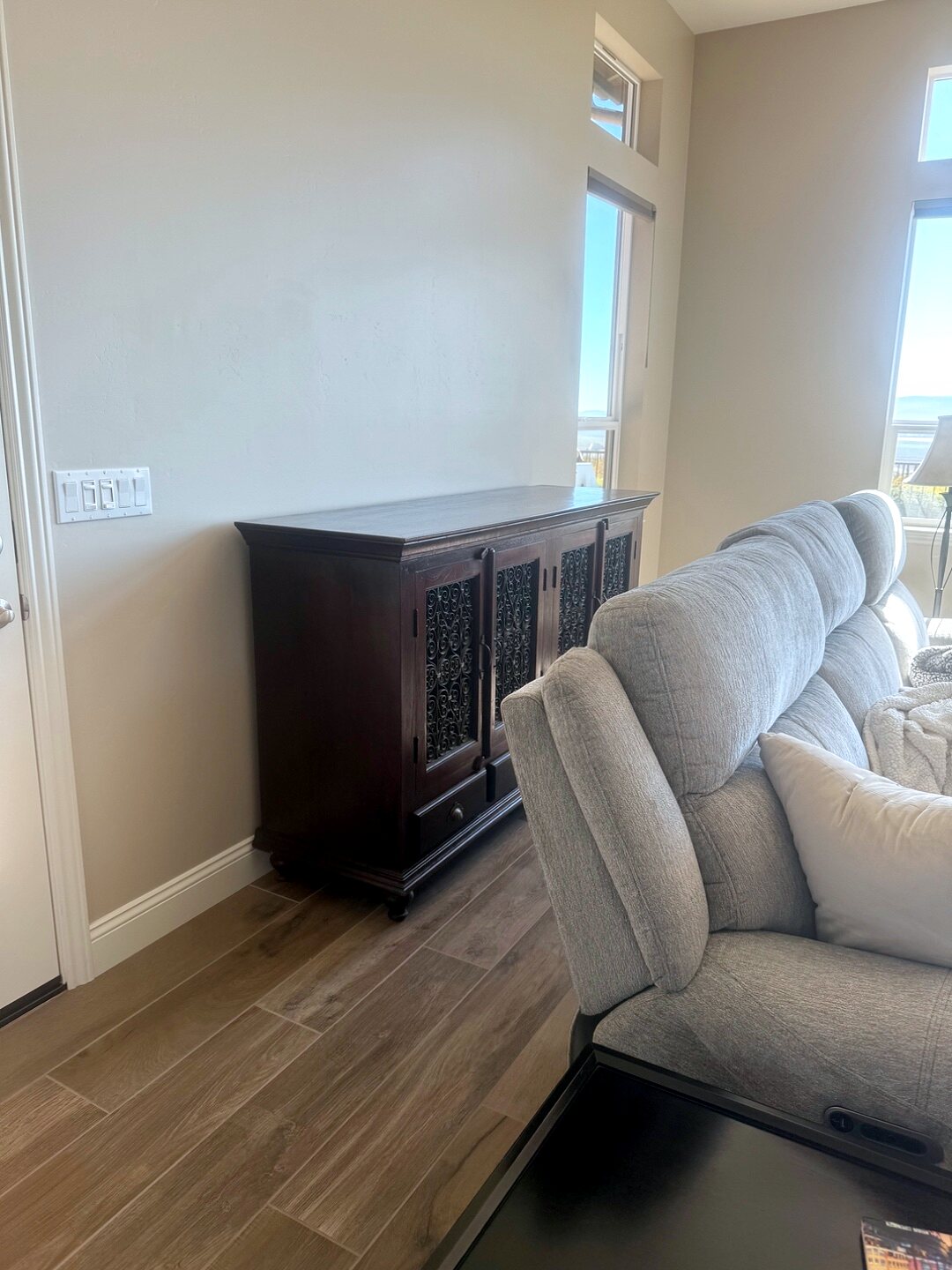 Living room wall before redesign — a bare sideboard against a plain beige wall