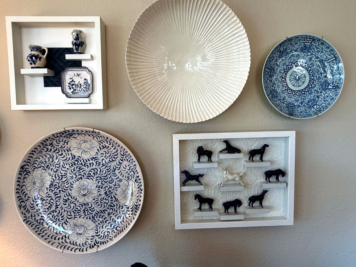 Plates and shadow boxes, mixed but never crowded — the spacing does the editing for you.